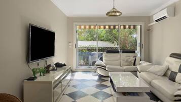 Un salon moderne avec un téléviseur à écran plat, un canapé, une table basse et un sol à motifs.