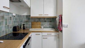 Eine Küche mit weißen Schränken, einer schwarzen Arbeitsplatte, einem Holzschneidebrett, einer Spüle und einem roten Handtuch, das an der Wand hängt.