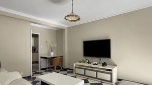 Ein modernes Wohnzimmer mit Flachbildfernseher, einem weißen Sofa, einem Couchtisch und einem karierten Boden.