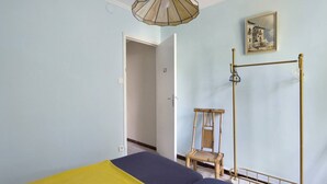 Ein Schlafzimmer mit Bett, Stuhl, einer Pendelleuchte und einem Bild an der Wand.