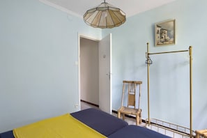 Une chambre à coucher avec un lit, une chaise, un luminaire suspendu et un tableau au mur.
