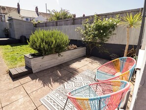 A patio with a raised planter, two colorful chairs, and a patterned rug. - 18 Kent Street (Cardiff)