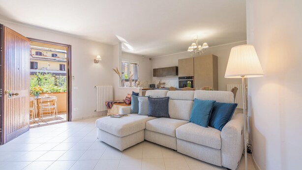 A living room with a sofa, a dining table, and chairs, a kitchen area, and a view through an open door. - Casa Vellaria – Charming Home with Garden in Tuscany near Pisa & Florence (Forcoli)