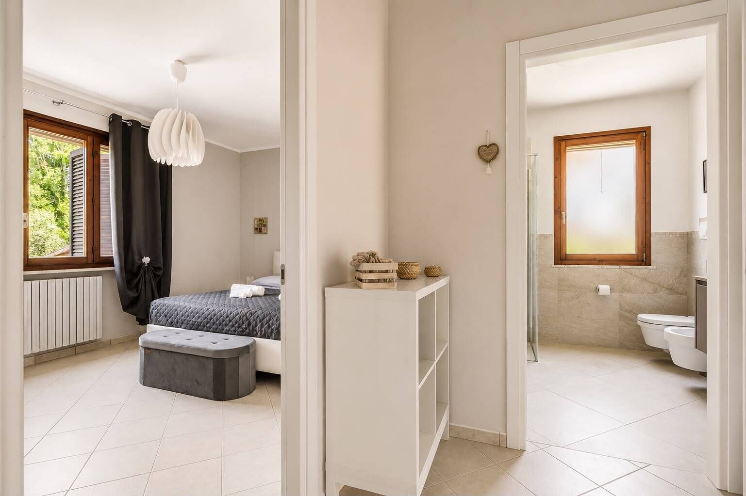 Quarto moderno com cama, mesa de cabeceira e luminária pendente.