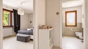Quarto moderno com cama, mesa de cabeceira e luminária pendente.