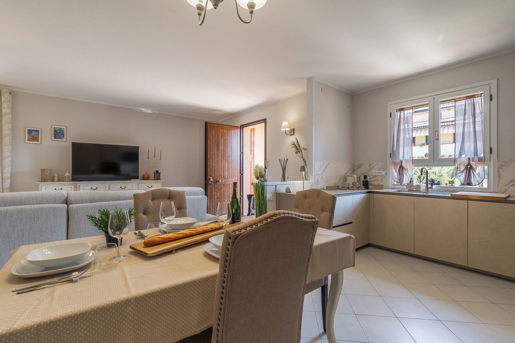 Un salon moderne comprenant un coin repas, un téléviseur et une cuisine avec une fenêtre.
