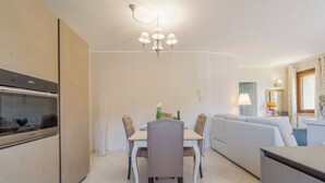 A modern kitchen with a built-in oven, a dining table with chairs, a sofa, and a chandelier. - Casa Vellaria – Charming Home with Garden in Tuscany near Pisa & Florence (Forcoli)