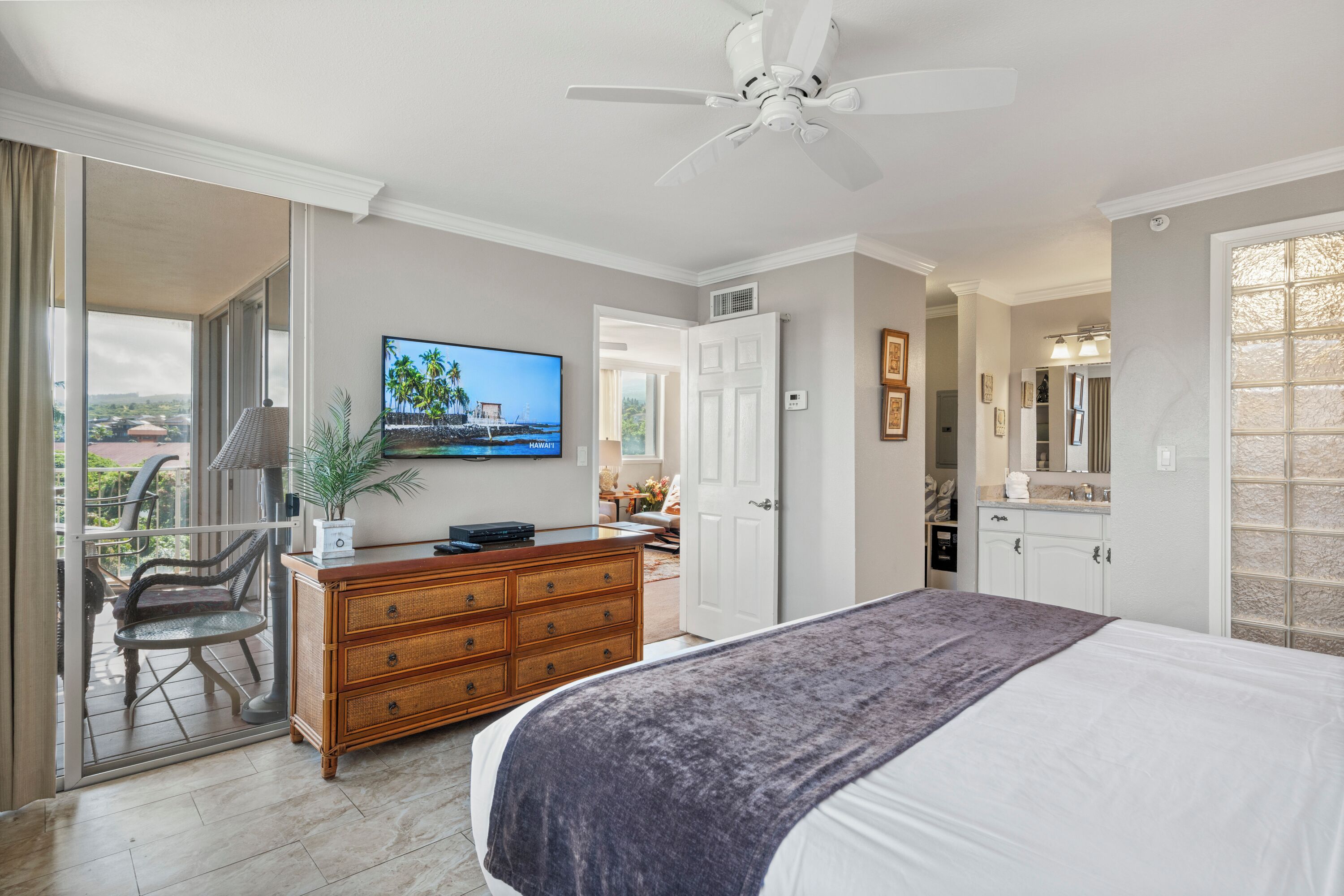 Ein Schlafzimmer mit Bett, Kommode, Fernseher und Deckenventilator.