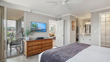 Ein Schlafzimmer mit Bett, Kommode, Fernseher und Deckenventilator.