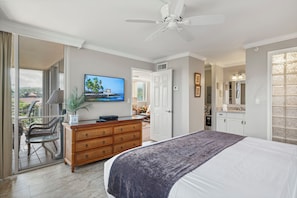 Un dormitorio con cama, cómoda, televisor y ventilador de techo.