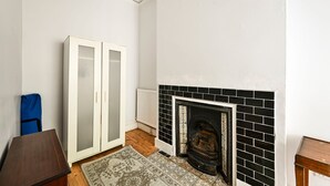 A room with a fireplace, a wardrobe, and a blue bag. - GuestReady - Stylish 1bed w Backyard in Clapham (London)