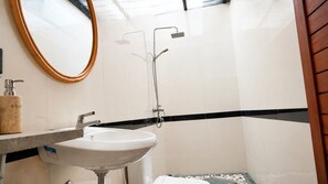 Ein Badezimmer mit einem weißen Waschbecken, einem Spiegel und einer Dusche.