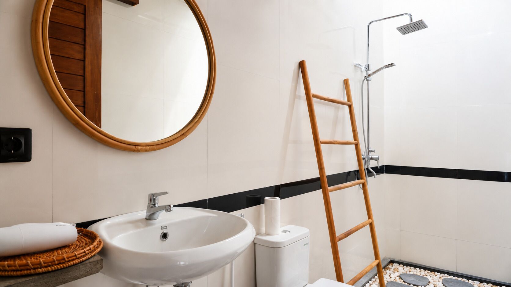 Een badkamer met een ronde spiegel, een wastafel, een toilet en een douche met een houten trapje.
