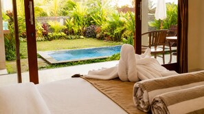 A hotel room with a bed, a view of a swimming pool, and a garden outside. - Eka Wisnu 2BR Private Pool Villa by TVM (Ubud)