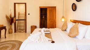 A hotel room with a bed, a wooden wardrobe, a small table, a vase with dried plants, and a hanging light fixture. - Eka Wisnu 2BR Private Pool Villa by TVM (Ubud)