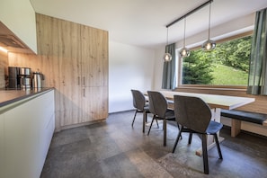 Eine moderne Küche mit einem Holzkorpus, einer Kaffeemaschine und einem Esstisch mit Stühlen.