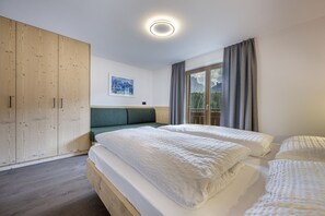Ein Schlafzimmer mit zwei Betten, einem Holzschrank, einem Gemälde und einem Fenster mit Vorhängen.