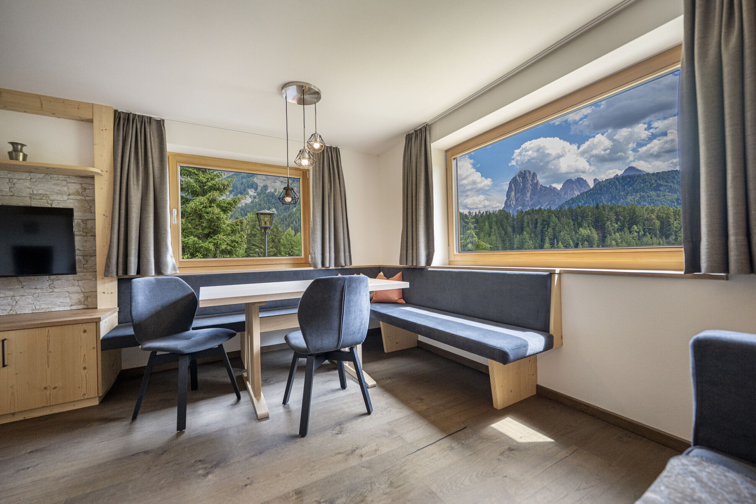 Eine moderne Küche mit Steinwand, integriertem Fernseher und einem großen Fenster mit Blick auf die Berge.