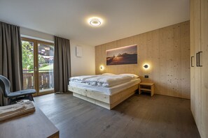 Ein Schlafzimmer mit einem Bett, einem Schreibtisch, einem Stuhl, einer Holzwand und einem Fenster mit Vorhängen.