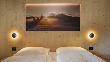A bedroom with two beds, a wall-mounted TV displaying a landscape, and two wall sconces.