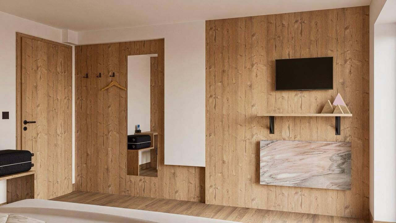 Une chambre avec une armoire en bois, un miroir, un t éléviseur fixé au mur et une œuvre d’art en marbre.