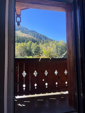 A wooden door with a view of a forested hillside. - BERGLIEBE - Boutique Apartment Saalbach (Saalbach)