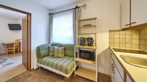 A compact living space with a sofa, a microwave, and a small kitchen area. - BERGLIEBE - Boutique Apartment Saalbach (Saalbach)