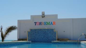 Un hotel llamado 'TOYREMAR' con piscina al frente.