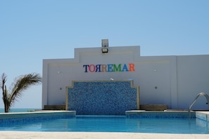 A hotel named 'TOYREMAR' with a pool in front.