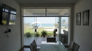Una habitación con puerta de vidrio que da a un patio con vista a la playa y al océano.