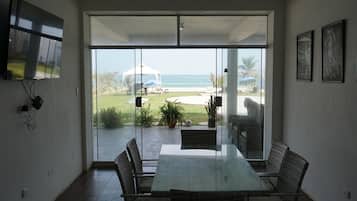 Una habitación con puerta de vidrio que da a un patio con vista a la playa y al océano.