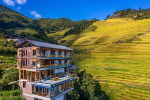 A multi-story building with terraces, surrounded by terraced fields and hills. - Longji B&B In Cloud (Guilin)