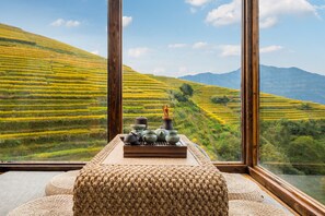 A room with a view of terraced fields through large windows.