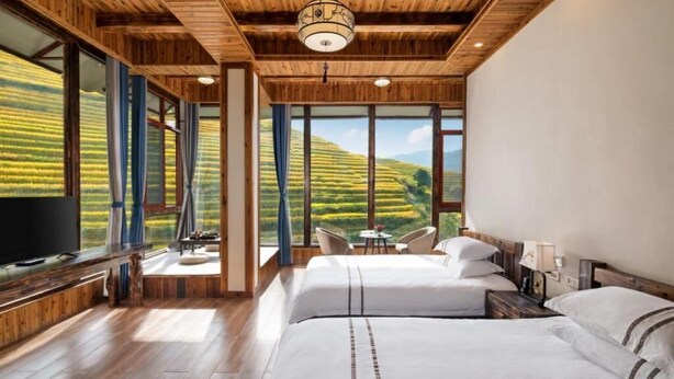 A hotel room with a large bed, a television, and a view of rolling hills.