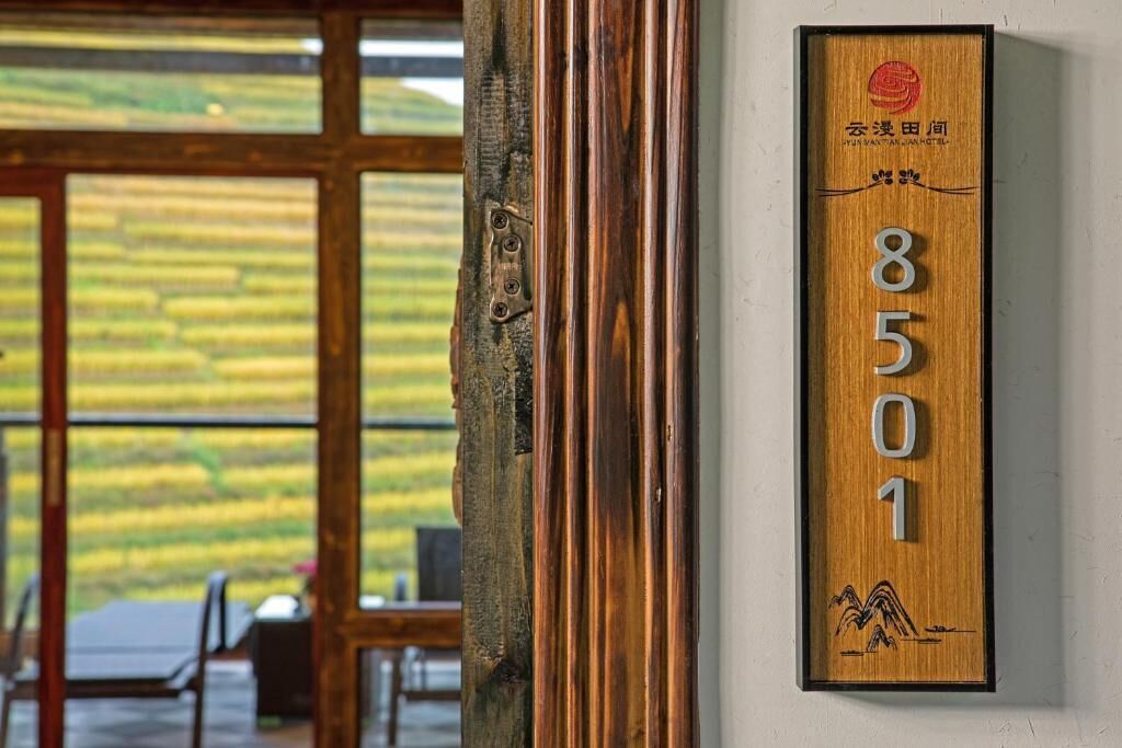 A wooden number plaque with the number 8501, a traditional Chinese design, and a view of a room with large windows and a table.