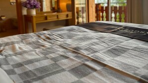 A bedroom with a checkered bedspread, a bedside table with a lamp, and a view of the outdoors through a sliding door.
