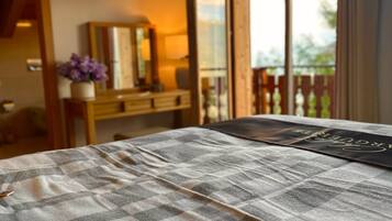 Une chambre avec une couvre-lit à carreaux, une table de chevet avec une lampe et une vue sur l’extérieur grâce à une porte coulissante.