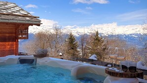 A hot tub with a snowy landscape and mountains in the background.