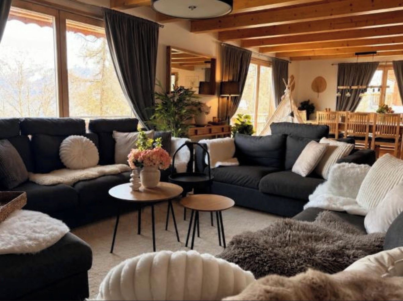 Een gezellige woonkamer met een hoekbank, een ronde salontafel en een open haard.