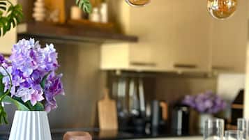 Un comptoir de cuisine orné d’un vase de fleurs violettes, d’une bougie et d’un porte-bougie en verre.