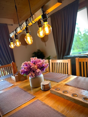 Une table à manger ornée d’un vase de fleurs, d’un panier en osier et d’une chaise en bois.