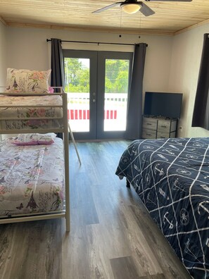 Una habitació amb literes, un escriptori amb televisió i un balcó amb vistes.