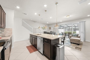 A modern kitchen with a central island, stainless steel appliances, and pendant lighting. - Blue Island Getaway only 8 miles to Disney (Clermont)