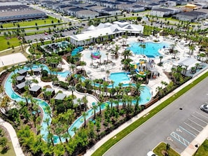 Ein Resort mit mehreren Schwimmbecken, Palmen und einem Parkplatz.