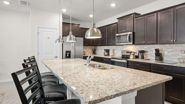 Una cocina moderna con encimeras de granito, electrodomésticos de acero inoxidable y armarios de madera oscura.