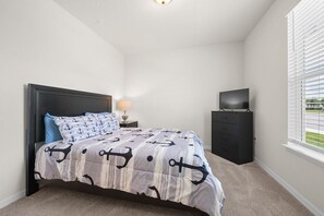 Ein Schlafzimmer mit einem Bett, einem Nachttisch, einer Kommode und einem Fernseher.