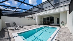Una piscina con techo de vidrio, sillas de descanso y un área de patio.