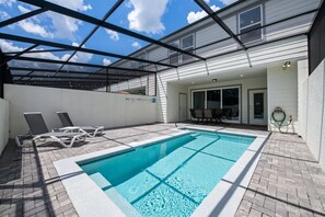 Ein Schwimmbecken mit Glasdach, Liegestühlen und einer Terrassenanlage.