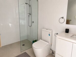 A modern bathroom with a glass-enclosed shower, a white toilet, and a sink with a mirror above it. - No.20 3B Pimpama Home (Pimpama)