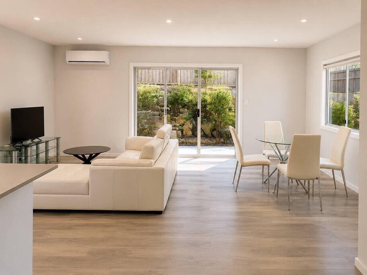 Una sala de estar moderna con un sofá, una mesa de centro de vidrio y un televisor.